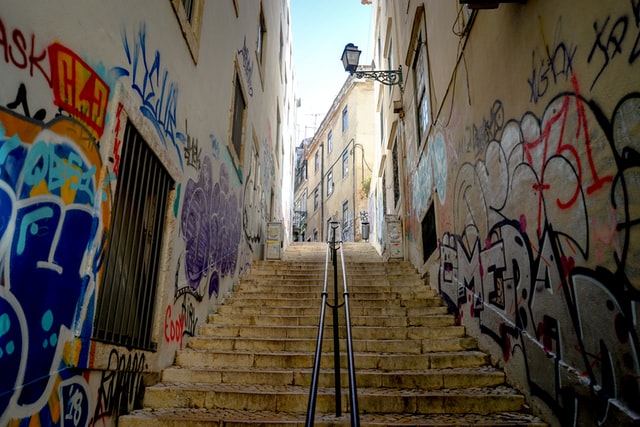 Picture of narrow street with staircase and graffiti in Lisbon, looking up