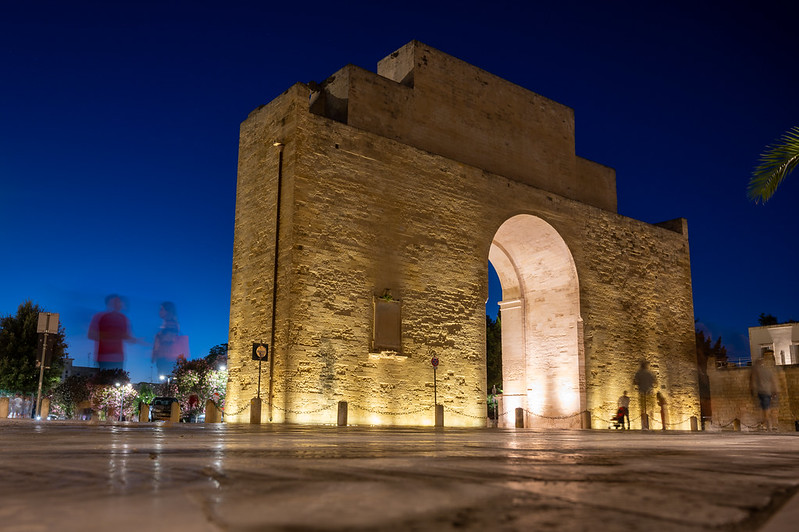 Old stone city gate (Porta Napoli in Lucce) just after dusk, lit-up from the ground