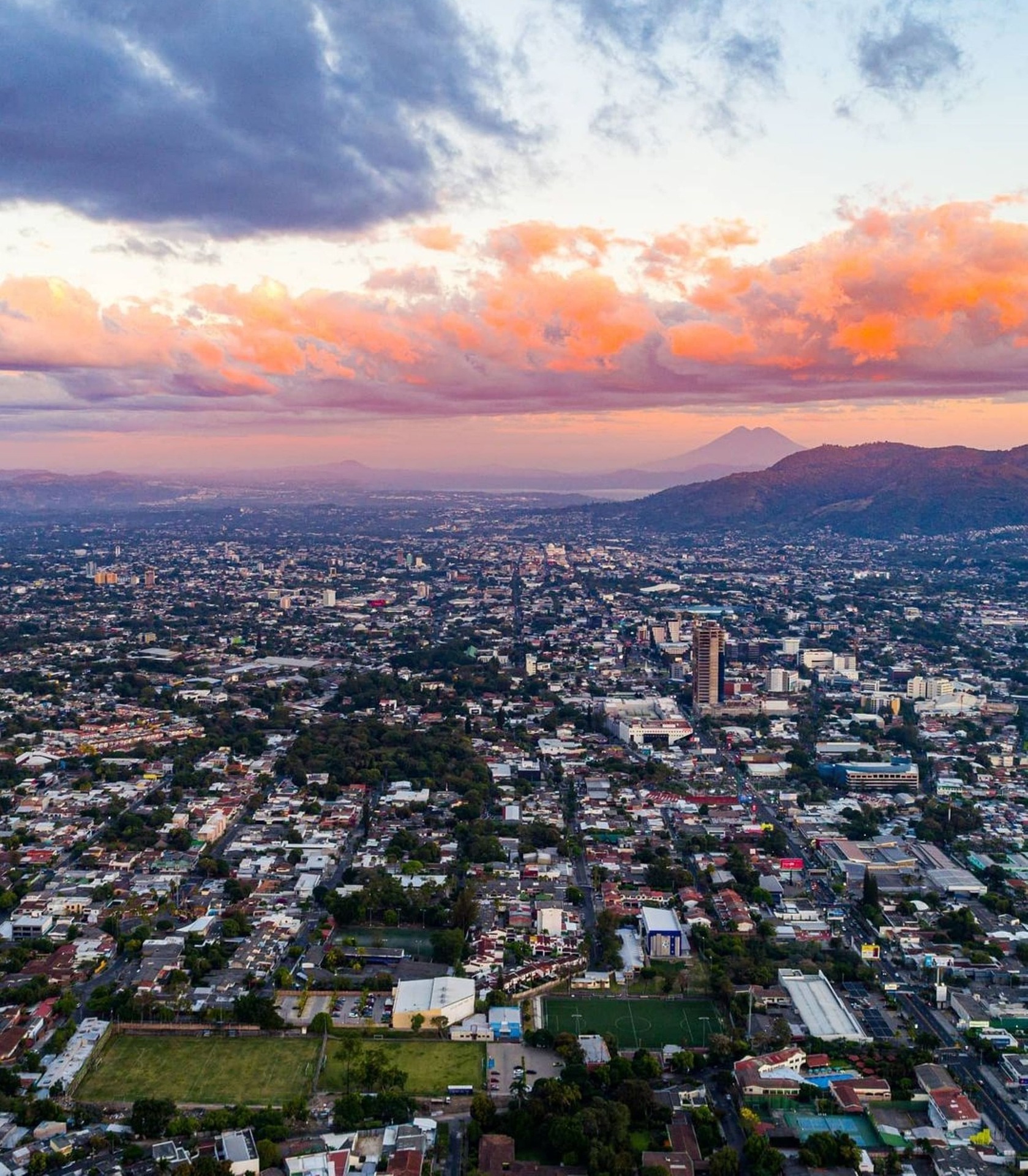 Aerial view of San Salvador with orange-coloured clouds and scenic mountains in the backdrop